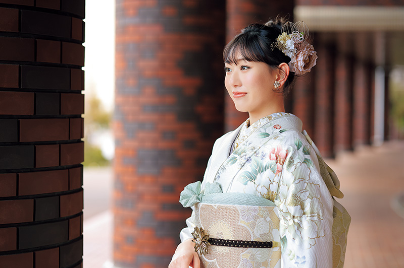 白い振袖に緑の帯揚げを付けた女性