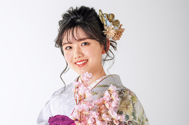 紫の振袖を着た大きめの花の髪飾りの女性